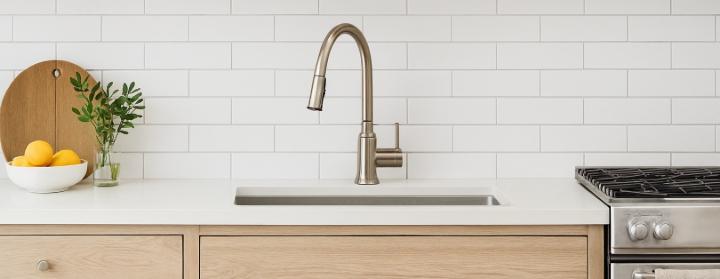 A modern kitchen sink with a pull-down faucet, set against a white subway tile backsplash.