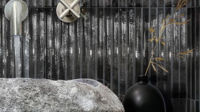 Bathroom sink with a stone basin and a dark vertical Linear liquirice 5x10 glossy glazed porcelain tile backsplash