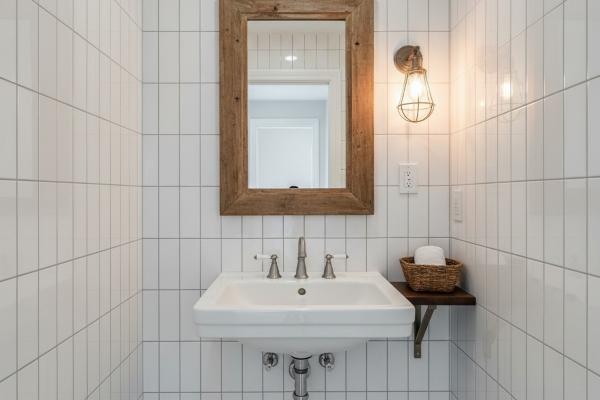 Vertical subway tile arrangement in small farmhouse powder room creating height-emphasizing wall surface