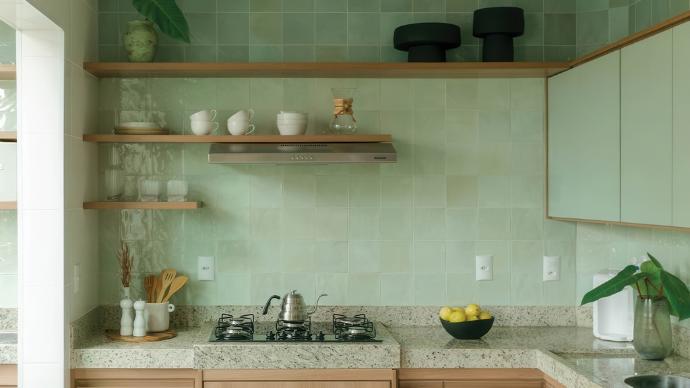A kitchen with a square sage green subway tile backsplash