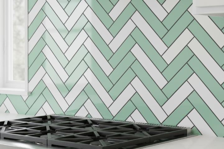 Herringbone pattern subway tile backsplash combining mint green and white tiles with dark grout