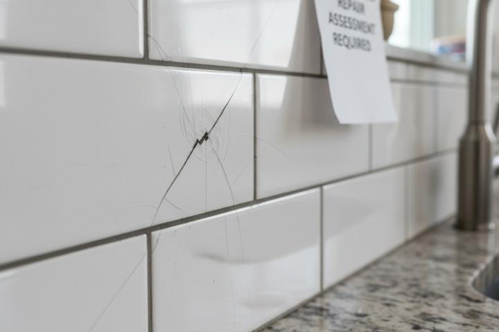 Cracked subway tile backsplash showing hairline fracture requiring professional repair assessment