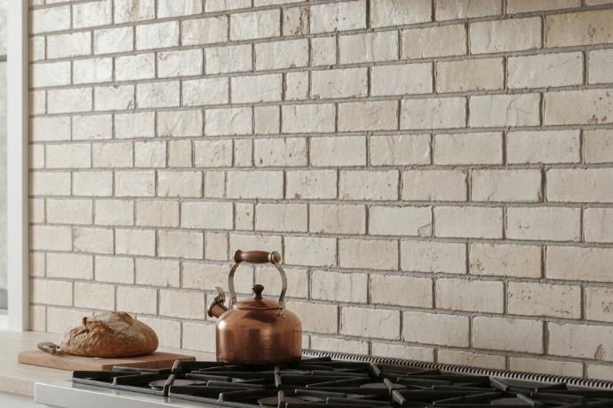 Brick pattern 2x4 subway tile in beige porcelain installed on modern kitchen backsplash with bronze kitchen appliances