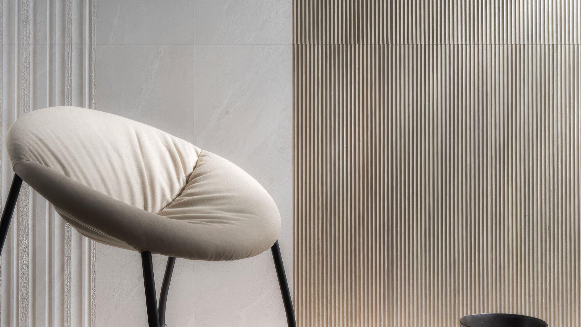 Modern interior with a cream armchair against a wall featuring Aura 13x39 Matte 3D Wood Look Ceramic Wall Tile.