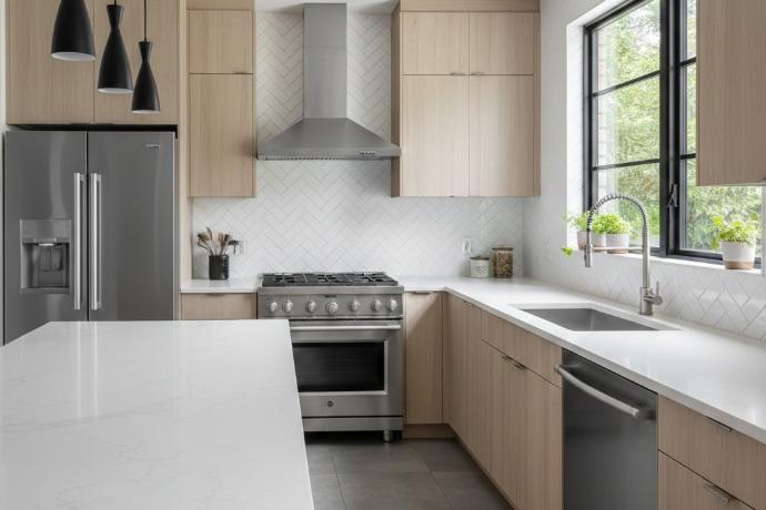 Contemporary kitchen featuring 3x9 herringbone subway tile backsplash extending from countertop to cabinets with stainless steel appliances
