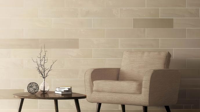 Modern interior wall featuring Obsidian 6x24 Glossy Large Format Subway Tile in a running bond pattern with a neutral accent chair and side table.