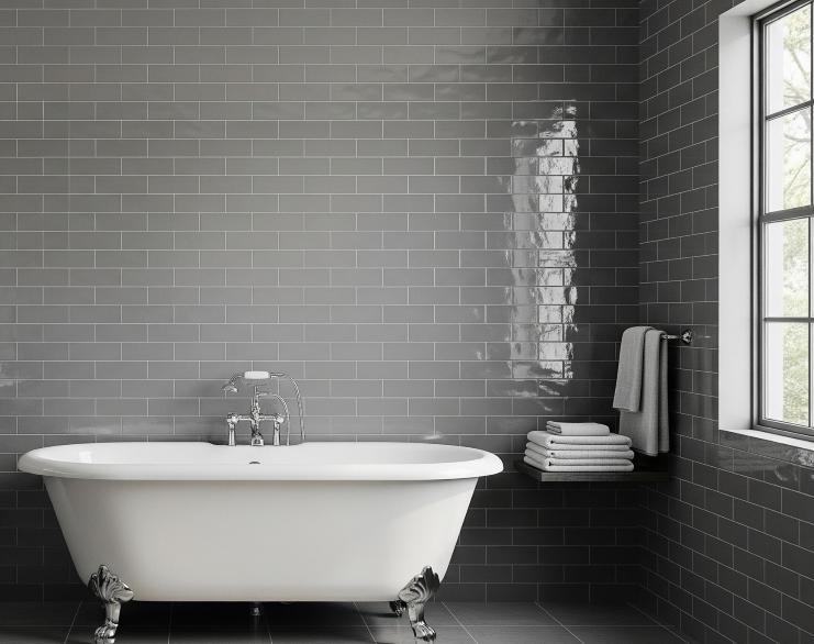 Glossy grey ceramic subway tile bathroom wall surrounding white freestanding tub