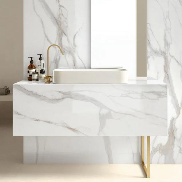 Calacatta Oro porcelain slabs used on floating vanity and shower walls with brass fixture accents.