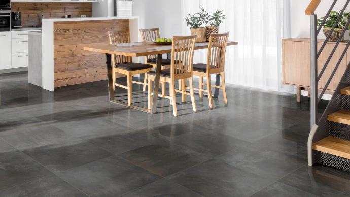 Cascade Titanium 12x24 metallic look porcelain tile - residential installation showing deep charcoal oxidized finish in contemporary open floor plan with warm wood accents