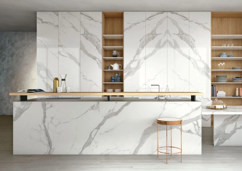 Modern kitchen with Classic Statuario porcelain slabs on island and bookmatched cabinet wall panels.