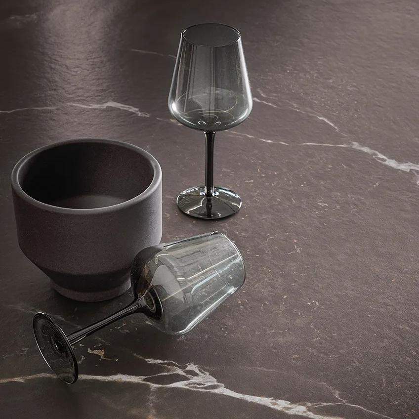 Andromeda porcelain slabs surface with wine glasses and dark ceramic bowl on countertop.