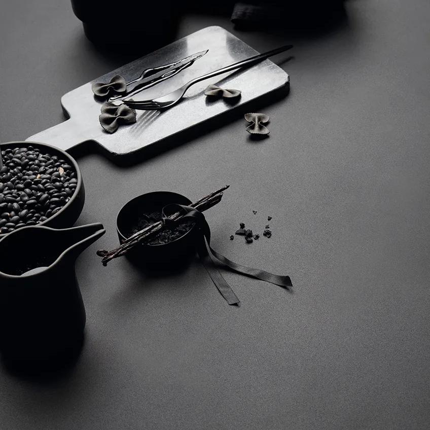 Food styling on Absolute Black porcelain slabs surface with bowls and kitchen accessories.