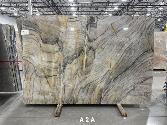 Book-matched quartzite slab with dramatic gray and gold veining in warehouse showroom