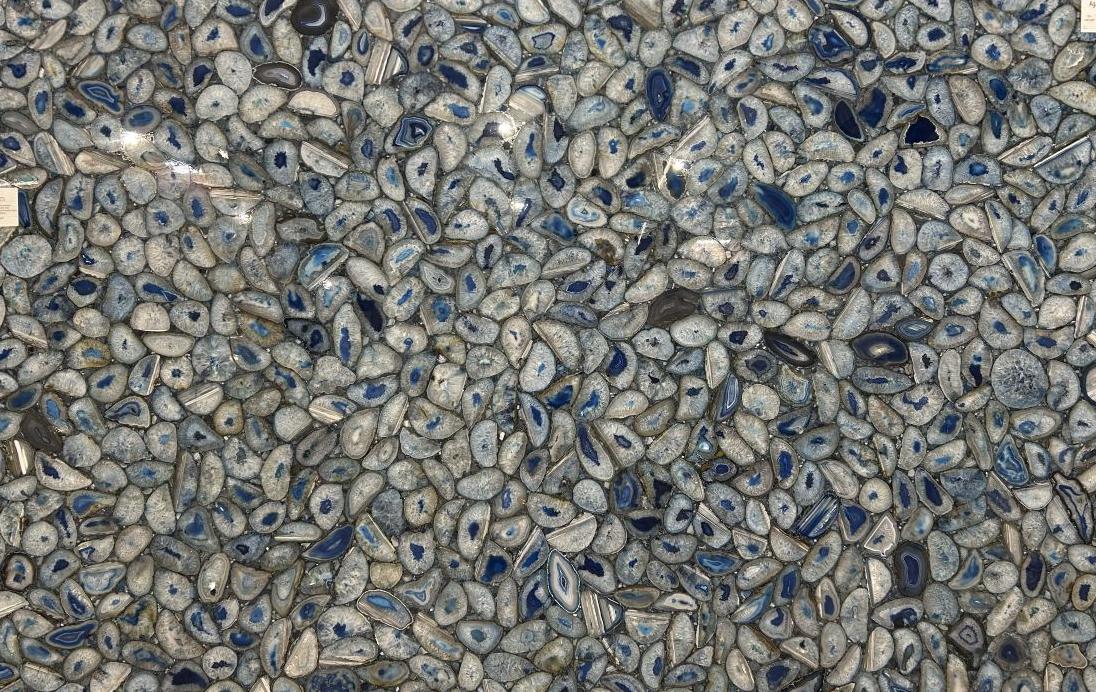 A large slab of Agate Azul semi-precious natural stone featuring a dense mosaic pattern of polished blue and grey agate geode slices