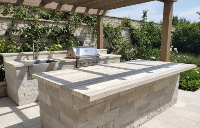 A modern outdoor kitchen featuring a large light-stone island