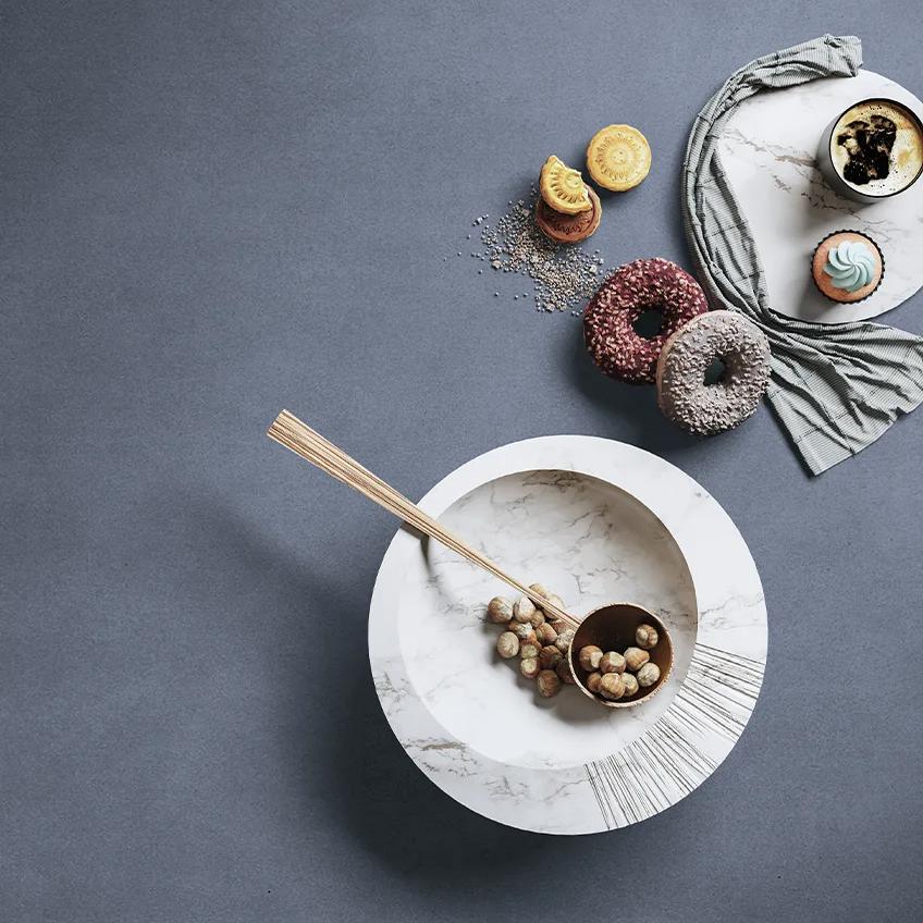 Antibes porcelain slabs countertop styled with white ceramic plates and decorative pastries display.
