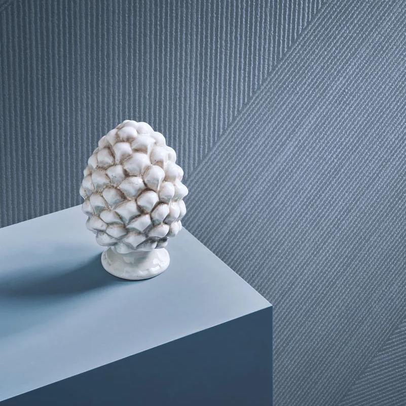 White decorative sculpture displayed on pedestal against textured Antibes porcelain slabs wall surface.