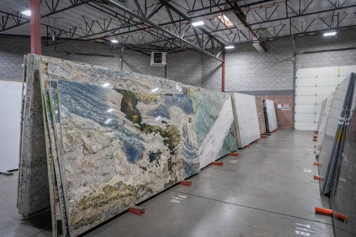 Large natural stone slabs with blue, green, and gold tones displayed in a stone yard