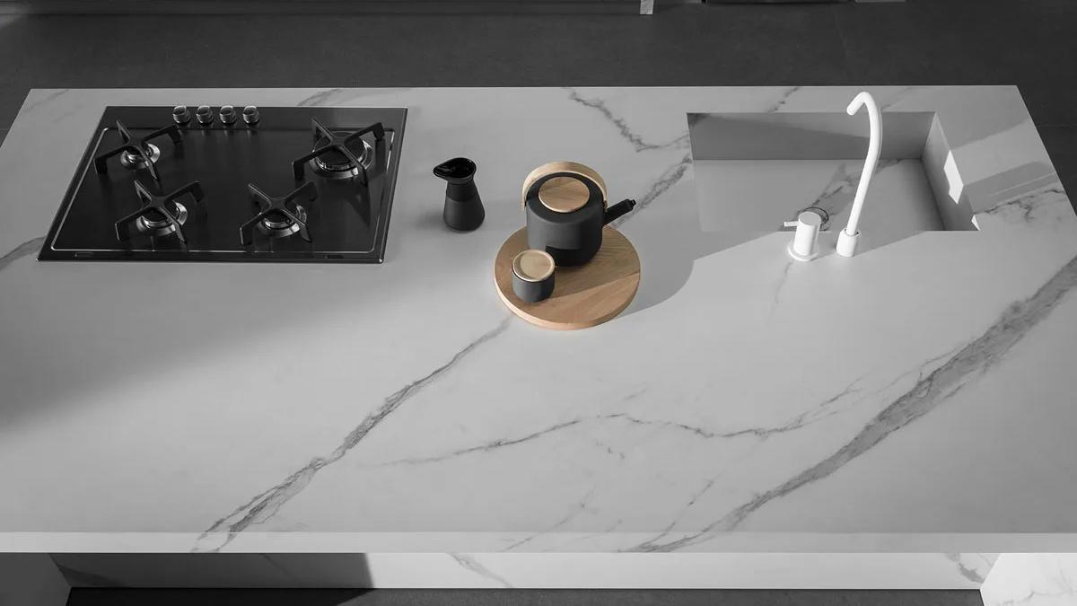 Extra Statuario porcelain slabs used as sleek kitchen countertop with modern gas stove