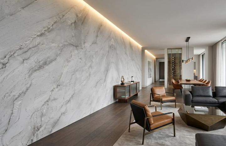 Full-height white quartzite slab feature wall with grey veining and cove lighting in a contemporary living room.